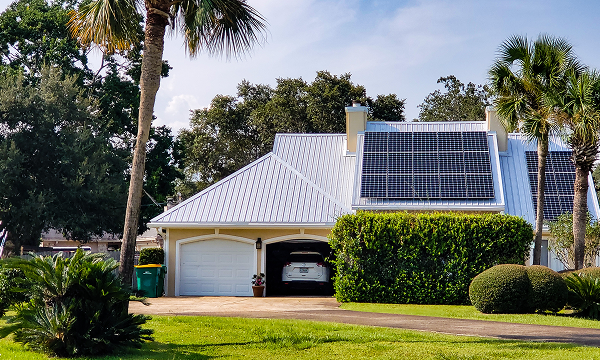 Modern residential home with solar panels installed on a white metal roof and a two-car garage
