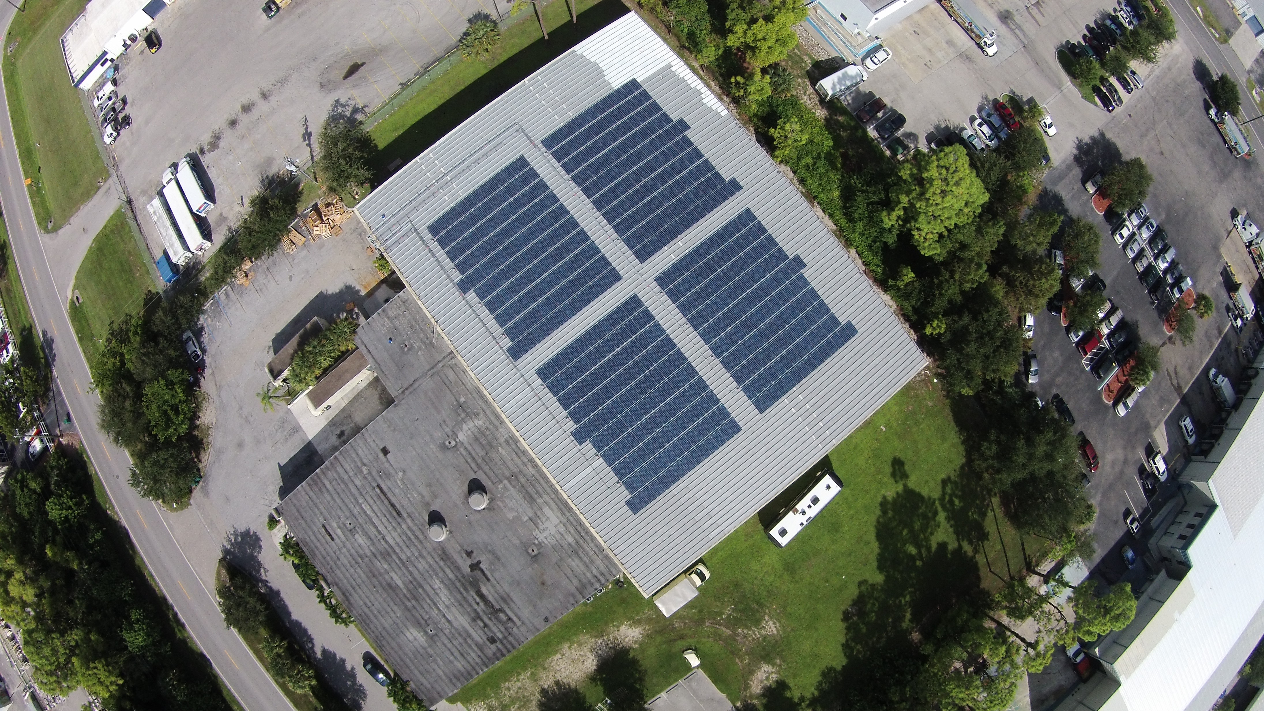 Aerial view of a commercial building with a large solar panel installation on a metal roof