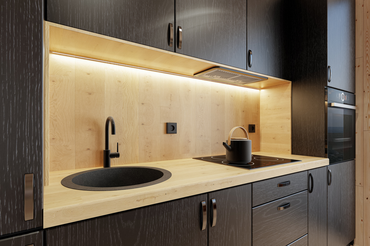 Modern kitchen interior featuring dark wood cabinets, light wood countertops, and sleek black fixtures