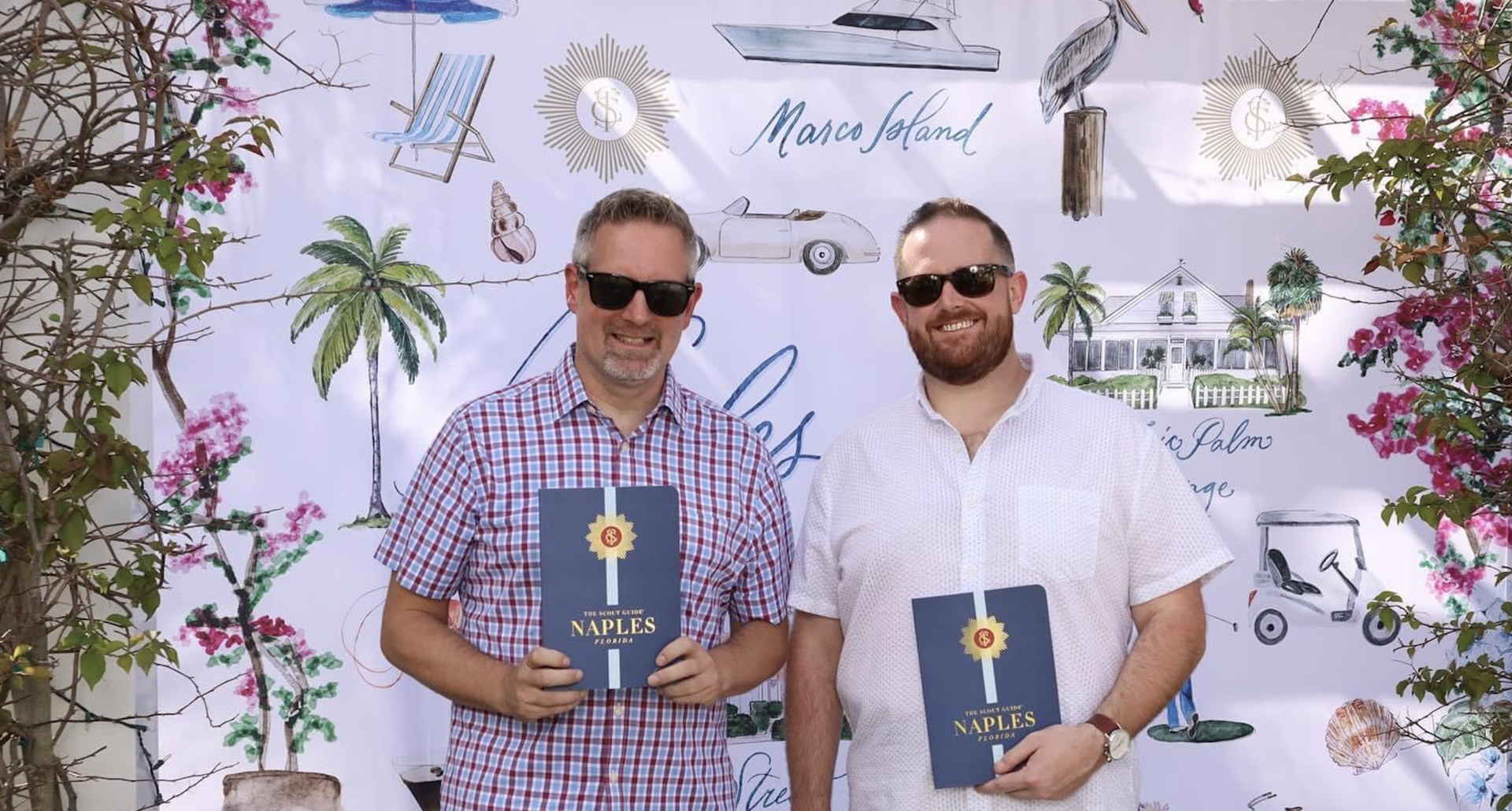 Two men holding The Scout Guide Naples books in front of a Naples, Florida themed backdrop