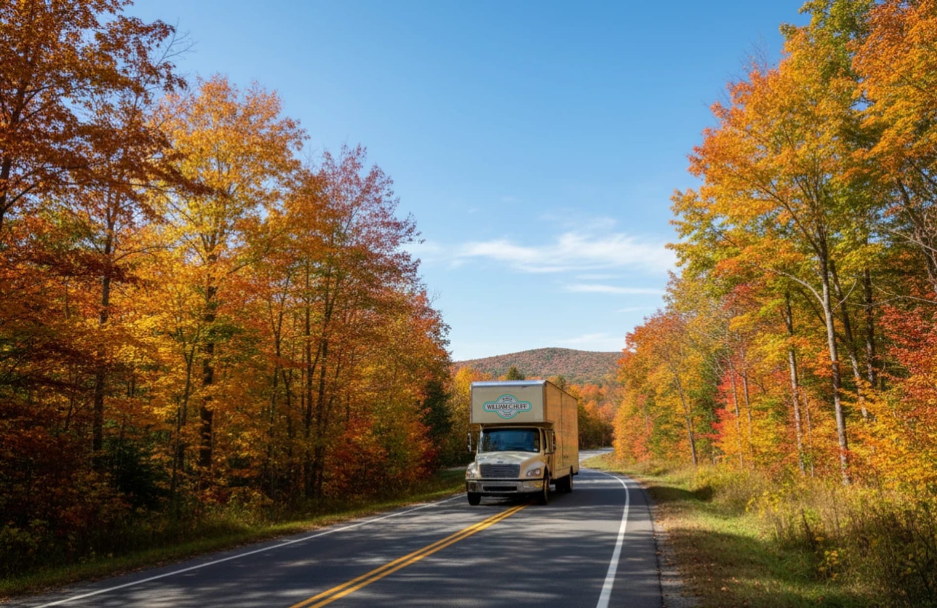 William C. Huff moving truck driving a scenic New Hampshire road through peak fall foliage